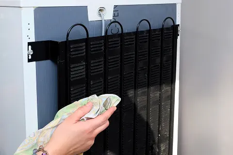 close-up-hand-cleaning-refrigerator-coils
